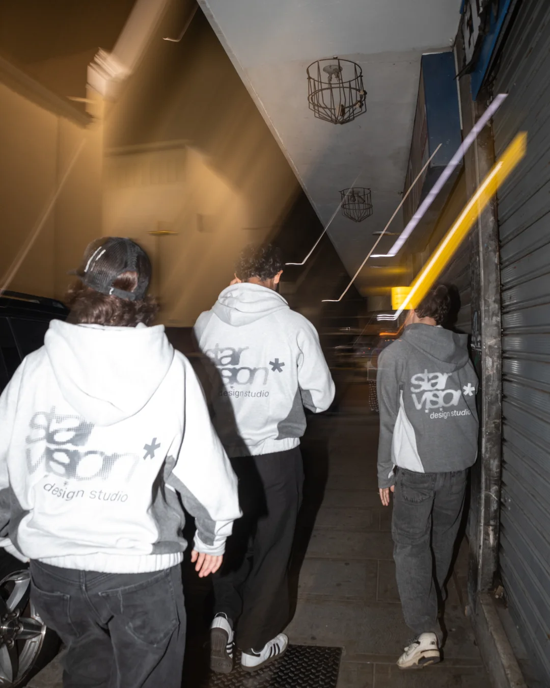 Tres personas con hoodies Star Vision recorren una calle de noche
