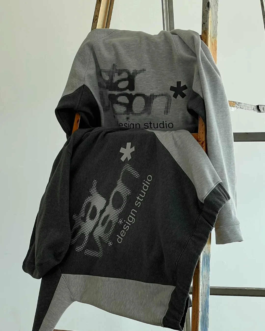 Hoodies Star Vision gris claro y gris oscuro sobre una escalera de estudio