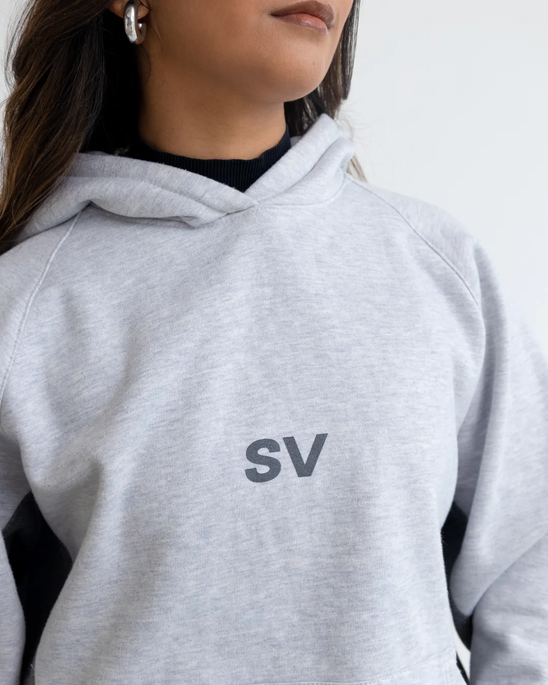 Detalle del logo SV sobre el hoodie gris claro