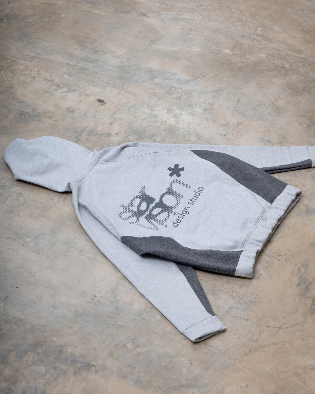 Hoodie Star Vision gris claro extendido sobre el piso del estudio