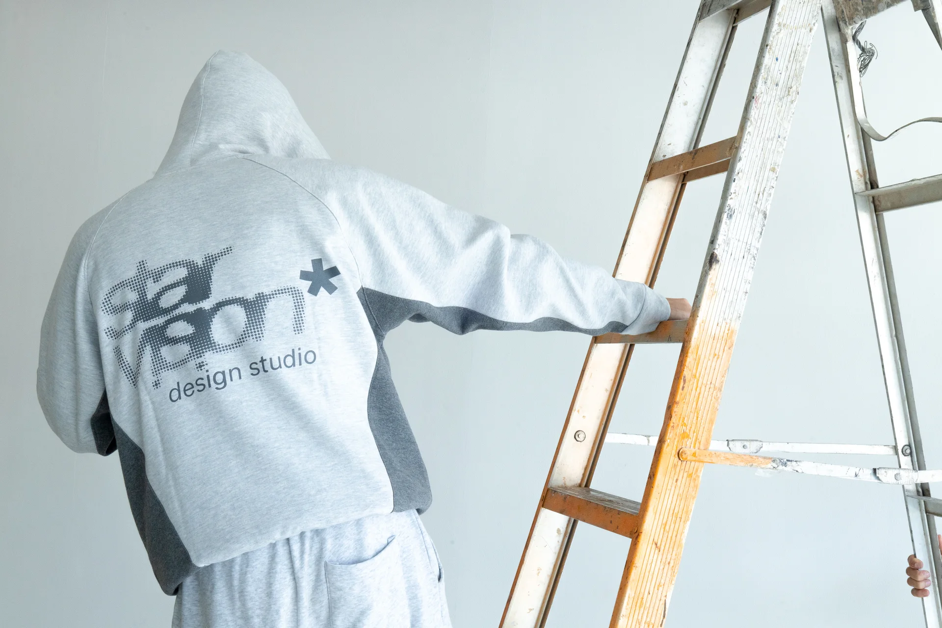 Hoodie Star Vision gris claro, fotografiado de espaldas junto a una escalera en el estudio